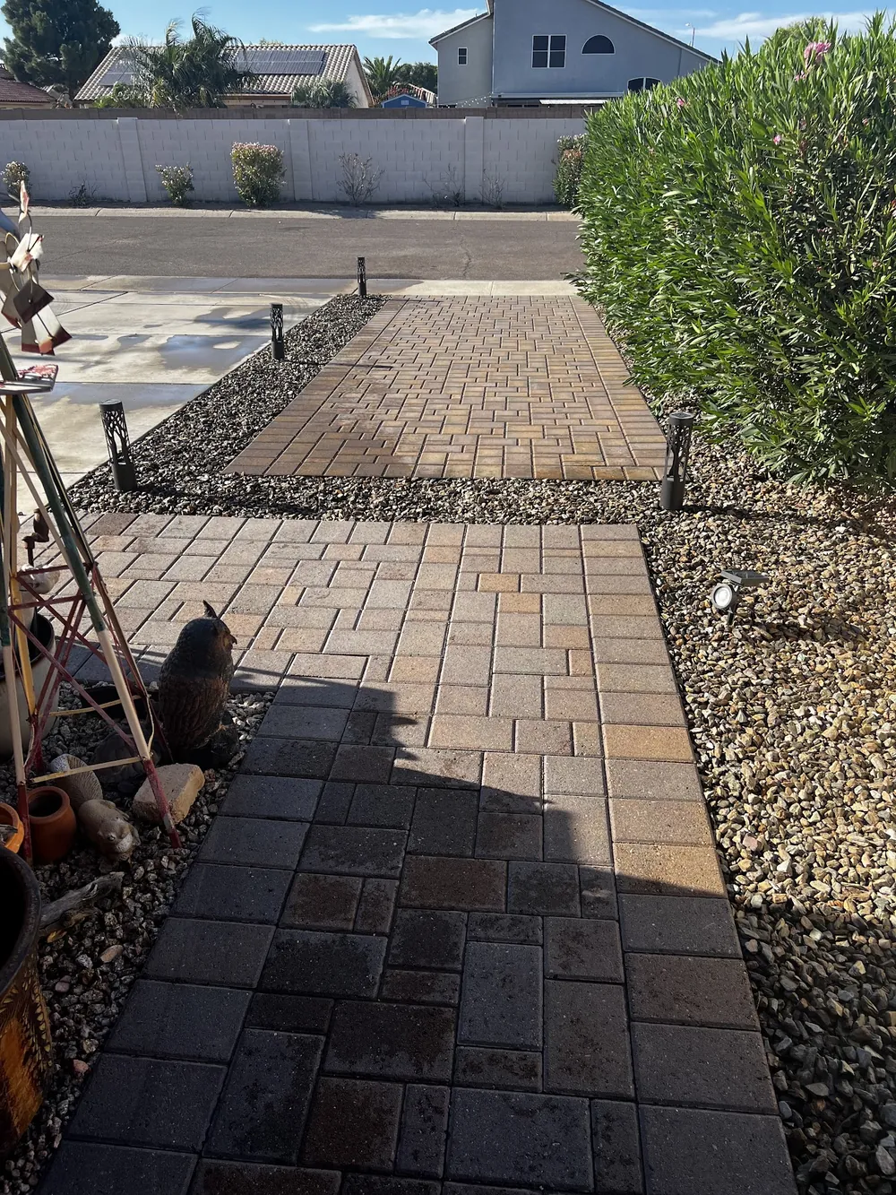 Narrow paver walkway running along a home beside a gravel bed