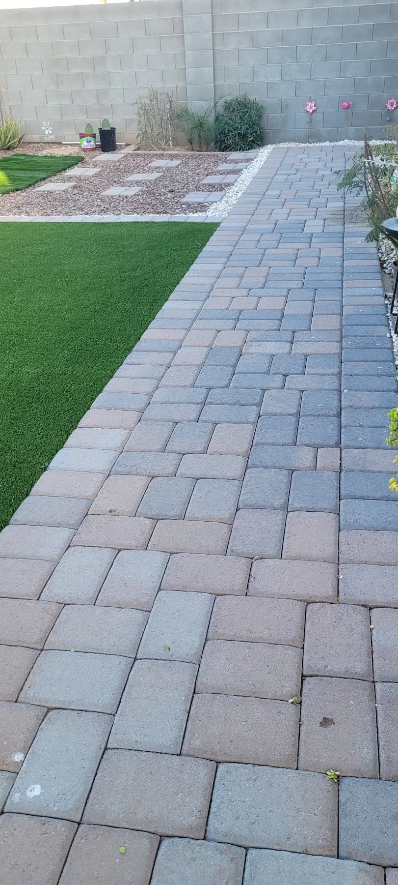 Paver walkway beside a turf strip along a block wall